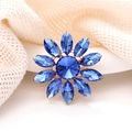 Vue détaillée d'une broche tournesol en cristal bleu sur un fond de tissu en maille beige - Rose bonbon