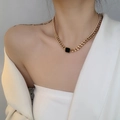Close-up of a gold chunky chain necklace with a black square pendant on a model - Gold Necklace
