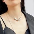 Detailopname van een zilveren slangenketting met witte parels gedragen door een model - Zilver Hanger Met Vijf Parels