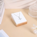 Detailed view of a silver star pendant with pearl and zircon on a premium display stand - 7*8 Pendant Rack / White Leather