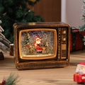 Macro shot of retro TV music box with Santa scene, glitter snow, and warm LED lighting - Gold TV Desk Santa