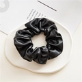 Détail d'un chouchou en cuir PU noir posé sur un plateau décoratif blanc élégant - Cuir Noir