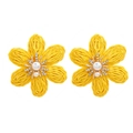Close-up of yellow raffia woven flower earrings with pearl and crystal center detail - Yellow