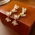 Detail von langen Schmetterlings-Ohrringen mit goldenen Zirkonia auf einer Lederbox - Gold Vier Schmetterlinge Quaste