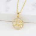 Macro detail of gold zodiac pendant with trident figure and sparkling crystal bezel - Aquarius