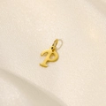 Macro shot of a polished gold letter P pendant on a textured beige fabric background - Letter-P