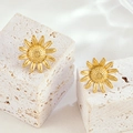 Polished gold sunflower stud earrings set displayed on natural stone pedestals - Gold Earrings