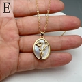 Detailed close-up of golden oval pendant with white mother of pearl and floral motif - Style E