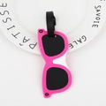 Pink sunglasses-shaped luggage tag with black strap on white plate for travel identity - Sunglasses