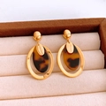 Detail view of oval resin pendant earrings with gold frame and Hand Made engraving - Gold Brown