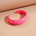 Dettaglio del bracciale rigido in acrilico rosa neon con texture lavica e design a C aperto - Rosa