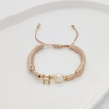 Detailed shot of handmade woven bracelet featuring a white pearl and golden letter H charm - Letter H