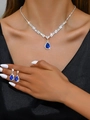 Detailed close-up of silver-plated necklace and drop-shaped blue sapphire earrings on model - 695 Royal Blue Necklace + Stud Earrings Set