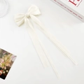 Macro shot of cream white ribbon bow hair clip with elegant long satin streamers - Double Streamer Bow - Alligator Clip / Cream
