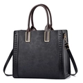 Elegante schwarze Handtasche mit Blumenprägung, braunen Griffen und goldener Hardware - Schwarz