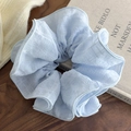 Dettaglio di scrunchie oversize a quadretti azzurri su legno con maglia accogliente - Blu / Blu