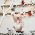 Gnomo di Natale in peluche rosa e marrone con barba bianca su sfondo festivo caldo - Rosa