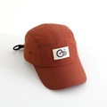 Detail view of brick red camper hat featuring white Go logo patch and breathable side eyelets - 52cm / Tan