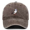 Close-up of pigeon embroidery and washed cotton texture on a brown baseball cap - Coffee