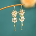 Foto macro de pendientes largos de flor dorada con perla y flecos de borlas largas - Borla de Flor Blanca Dorada