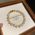 Dettaglio macro del bracciale a quadrifoglio placcato oro 18K con zirconi brillanti - Stile Quadrifoglio Continuo con Zirconia Completa / Oro-Bianco