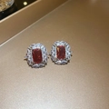 Dettaglio degli orecchini vintage con zircone rosso e pietre trasparenti su vassoio d'oro - Orecchini a perno in argento - Orecchini quadrati rosa
