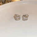Macro-opname van zilveren gelaagde oarcuffs met zirkonia op een witte porseleinen ondergrond - Zilver