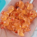 Handful of translucent orange resin ducks with red beaks for DIY crafts and decor - Orange