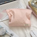 Detailed view of pink floral makeup bag with textured dot fabric and brand label - Pink Polka Dot