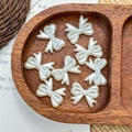 Detail shot of pearlescent white resin butterfly beads in a natural wooden tray for DIY crafts - Engraved Bowknot