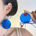 Deep blue round tassel earrings with woven bow and red beads detail on model - Klein Blue Contrast Color Earrings / Klein Blue