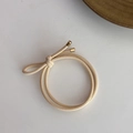 Close-up of beige elastic hair tie with minimalist gold metallic decorative clasp detail - Beige