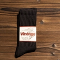 Deep brown retro ribbed cotton sock with a vintage beige paper label on a dark wood background - One Size(EU 35-44) / Black