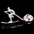 Macro detail of silver skier brooch with ski poles and matching butterfly clutch back - Skier