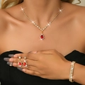 Detailed view of luxury gold necklace, earrings and bracelet set with red stones on a model - Three-Piece Set / Gold Red