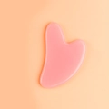 Detailed view of a heart-shaped pink resin facial massage tool on an orange background - Resin / Pink