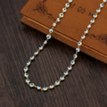 Goldene Evil Eye Halskette mit bunten Emaille-Perlen auf einem Vintage-Buch - Weiß