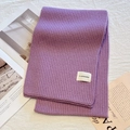 Thick purple ribbed knit winter scarf with a white woven label on a soft background - Purple