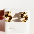 Golden wavy spiral earrings featuring a polished sculptural metal design on white stand - Stud Earrings / Gold