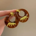 Detailed macro view of amber resin hoop earrings with gold leopard relief charms - Gold Leopard Embossed Hoop Style (Size 16 Silver Earring Post - Gold - Coffee)