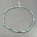 Detail of blue-green natural stone necklace with silver lobster clasp on stone background - Apatite