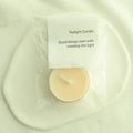 Single white tealight candle in clear bag with decorative label on a ceramic tray - Champagne (Blood Orange)