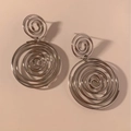 Details von silbernen Spiral-Ohrringen im minimalistischen Design auf rosa Grund - Spiral-Spleiß-Stil (PDE2523) / Silber