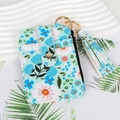 Detail of floral card holder with gold snap, side zipper, and elegant tassel charm - Blue Floral