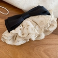 Détail des bords en dentelle brodée et du nœud en satin noir sur la pince à cheveux - Pince à ressort avec nœud en dentelle patchwork noir et blanc