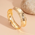 Detailansicht eines glänzenden goldenen Metallarmbands mit Scharnierverschluss - Gold