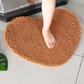 Absorbent brown heart-shaped chenille bath mat with soft non-slip texture on tile floor - Champagne