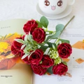 Detail of red artificial 10-head roses bouquet with silk leaves on a magazine - Red