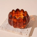 Macro detail of amber resin acrylic bangle showing tortoise shell texture and elastic cord - Amber