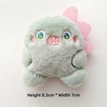 Detail view of a 8.5cm tall mint green plush monster charm with pink fins and embroidery - Green